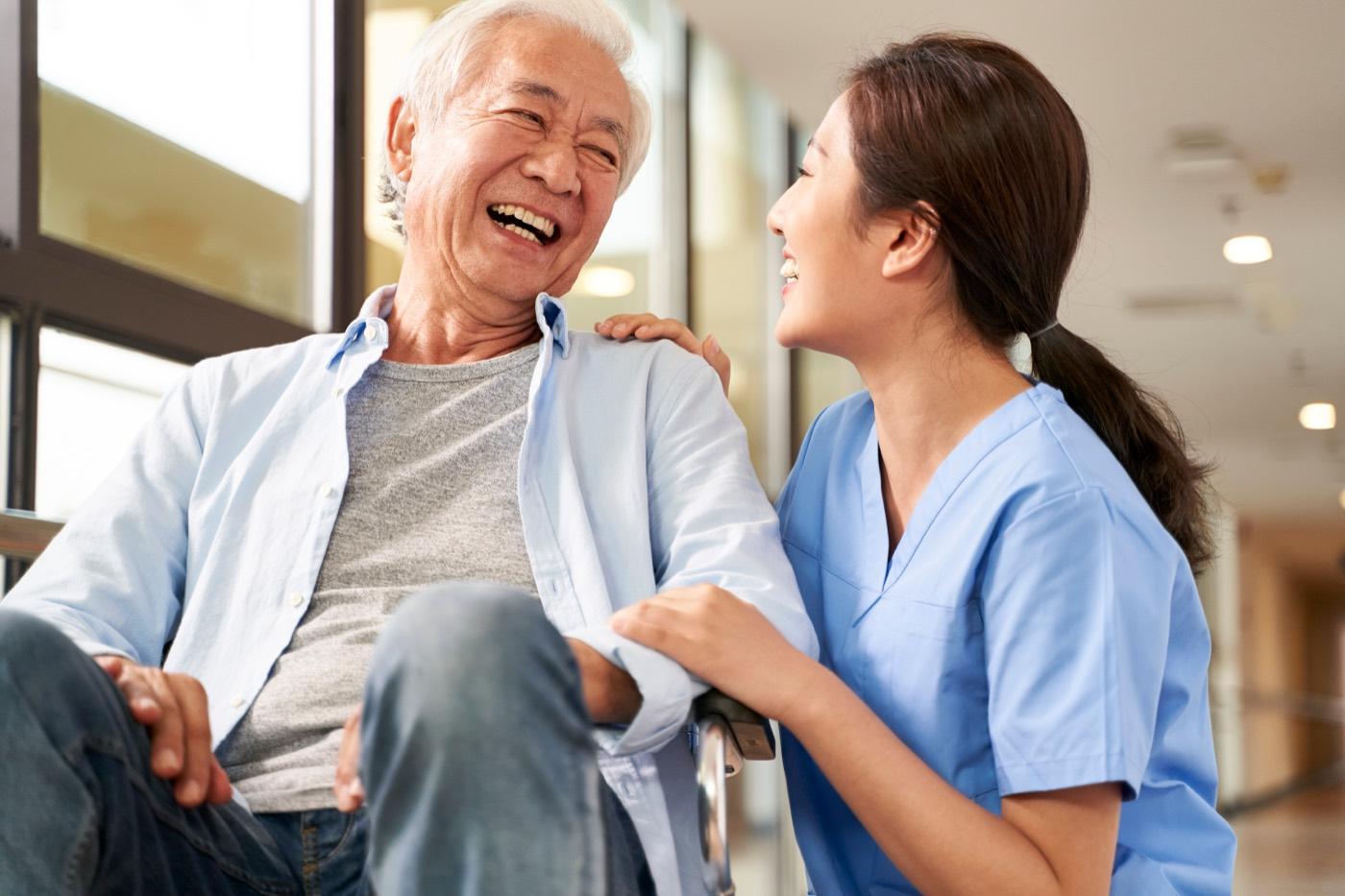 A Gentle Touch caregiver shares a warm, easy conversation with an older man in his living room.