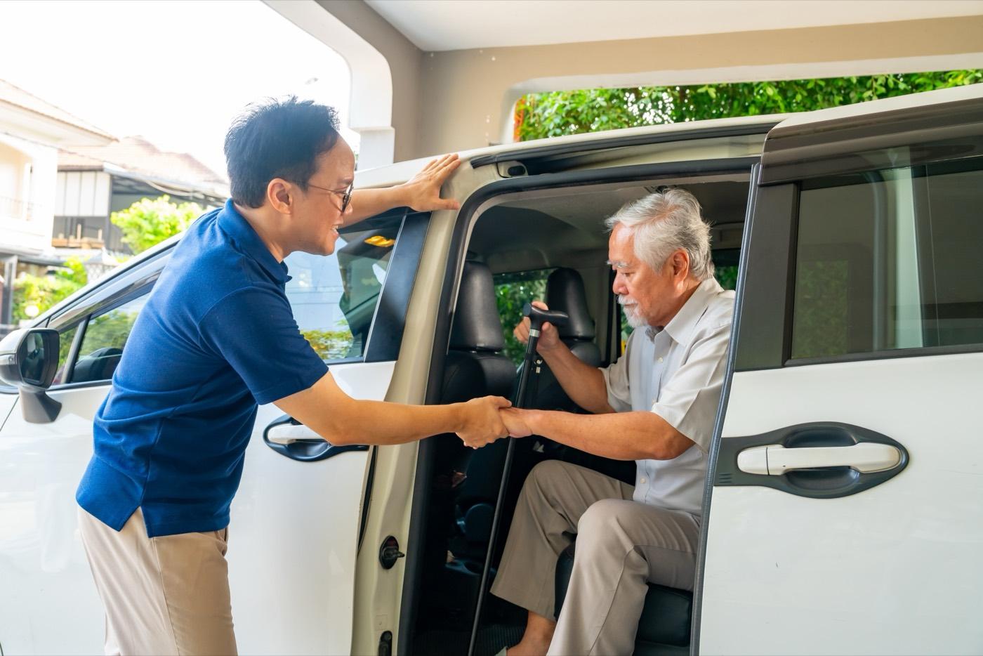 A caregiver steadies an older man as he moves safely.