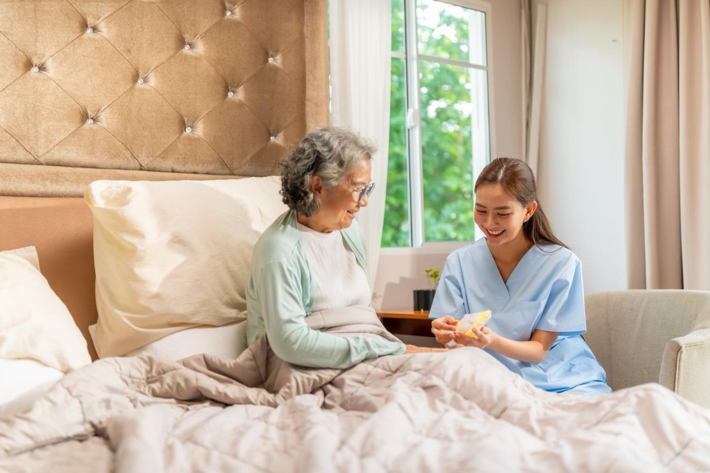 A caregiver sits with an older woman, reviewing her daily routine together.
